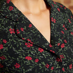 Close-up of the notched collar and black button-front bodice on a vintage-inspired corduroy dress with red floral print.