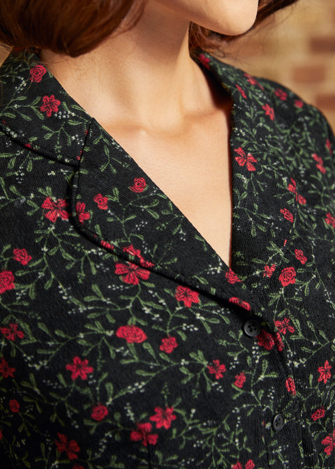 Close-up of the notched collar and black button-front bodice on a vintage-inspired corduroy dress with red floral print.