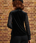 Rear view of the Winifred Waistcoat Vest featuring a solid black velvet-look back, worn over a sheer black lace blouse with long sleeves.