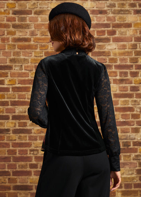 Rear view of the Winifred Waistcoat Vest featuring a solid black velvet-look back, worn over a sheer black lace blouse with long sleeves.