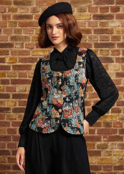 A woman wearing a black lace long-sleeve blouse, a black vest with a colorful floral tapestry print, a black skirt, and a black beret, standing against a brick wall.