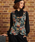 Model wearing the Winifred Waistcoat Vest in Tapestry Tabbies with a black lace bow blouse, black trousers, and beret, showing the tailored cat tapestry design and gold buttons.