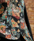 Close-up of a ModCloth vintage-inspired cat and floral tapestry vest showing ornate gold-tone buttons, tailored seams, and subtly flared front hem.