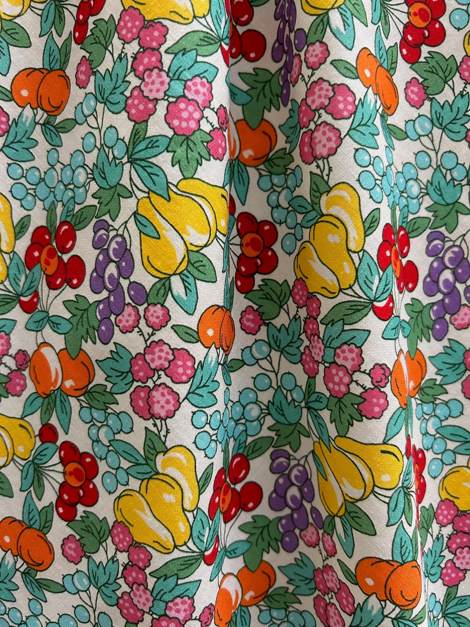 Close-up of a colorful floral and fruit patterned fabric.