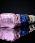 Colorful makeup bags stacked on a reflective black surface with a dark background