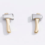 Pair of gold and silver axe-shaped earrings on a light gray background