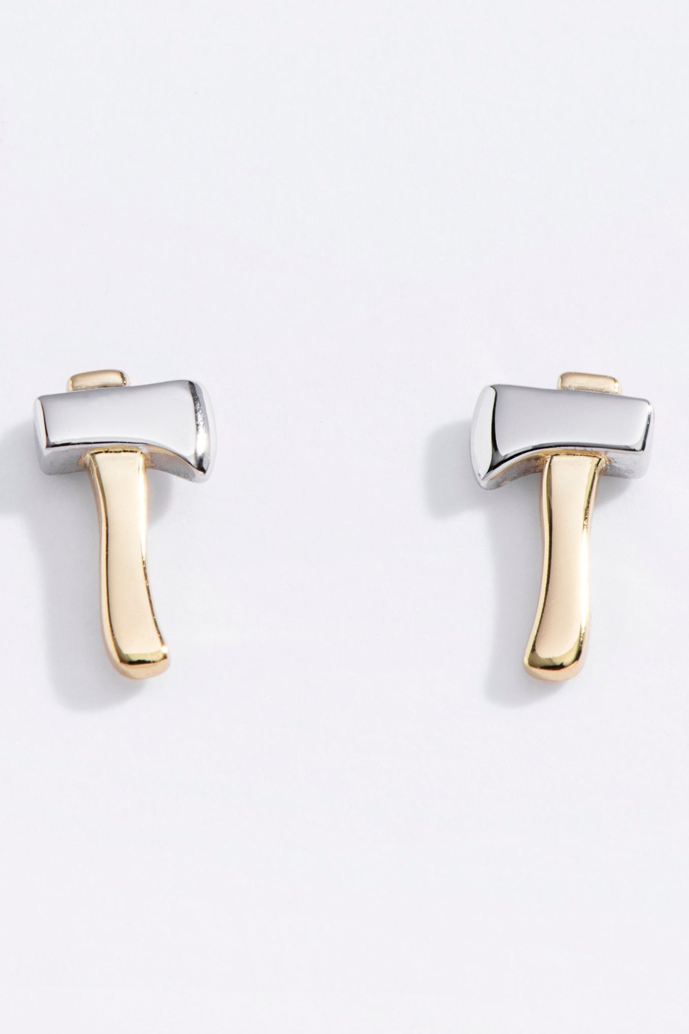 Pair of gold and silver axe-shaped earrings on a light gray background