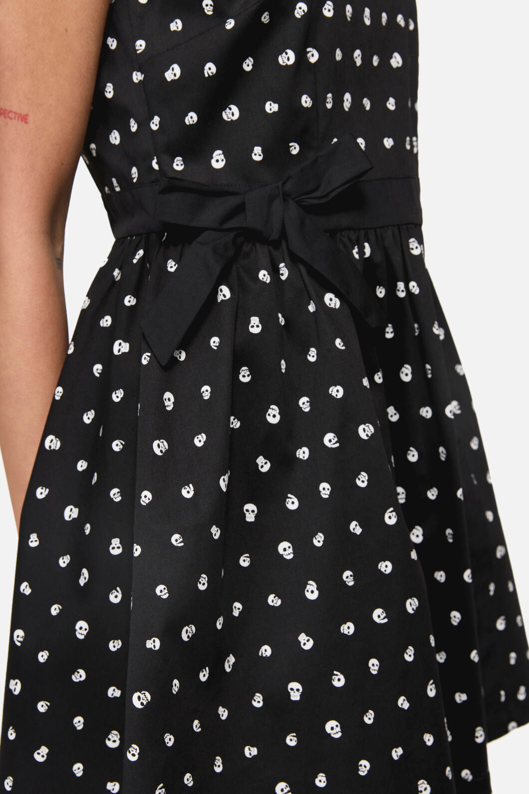 Black dress with white skull pattern and tie waist on a plain background