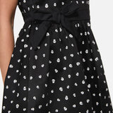 Black dress with white skull pattern and tie waist on a plain background