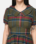 Woman wearing a plaid dress with a neutral background
