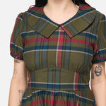 Woman wearing a plaid dress with a neutral background