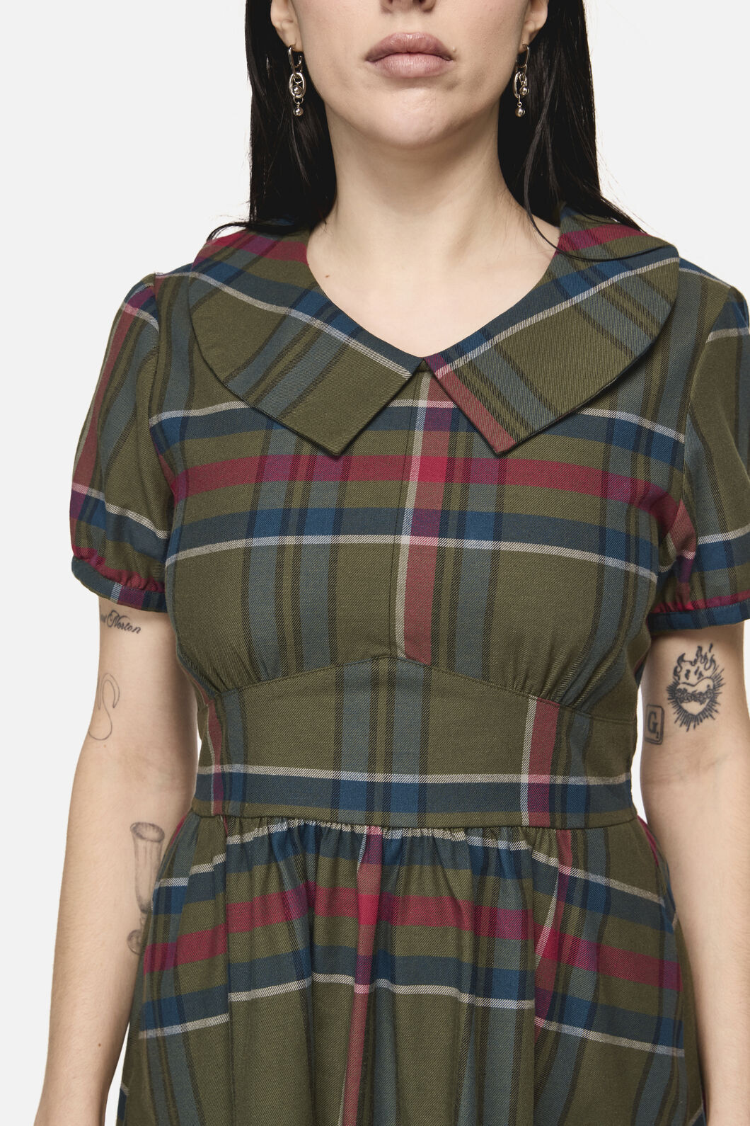 Woman wearing a plaid dress with a neutral background
