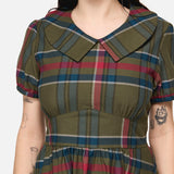 Woman wearing a plaid dress with a neutral background