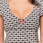 Black and white checkered dress with hearts and a red bow detail on a plain background