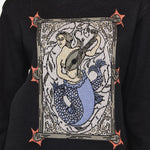 Black sweater with a mermaid graphic design on a plain background