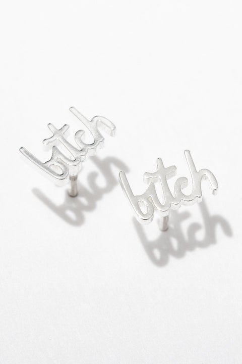 Silver 'bitch' earrings on a white background