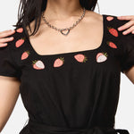 Black dress with strawberry patterns worn by a woman 