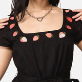 Black dress with strawberry patterns worn by a woman 