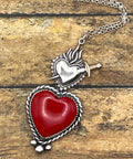 Heart-shaped pendant with a sword on a chain against a wooden background