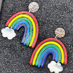 Colorful rainbow-shaped earrings with cloud designs on a black background