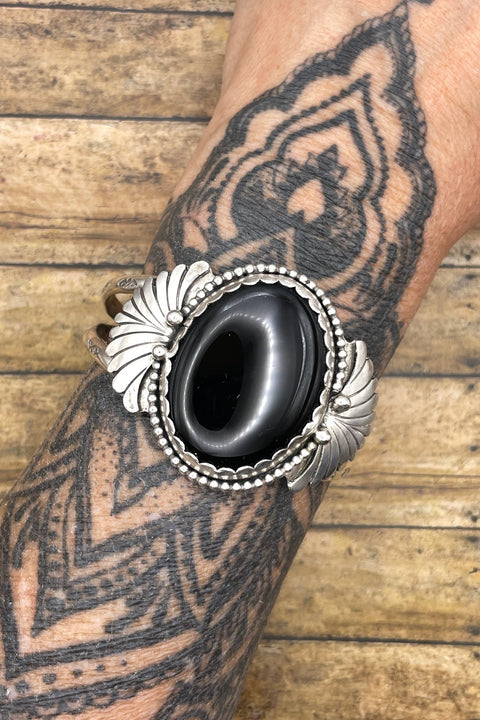 Artisan made sterling silver cuff bracelet with large black onyx center stone and fan detail on sides.