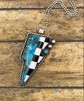 Necklace with a checkered and turquoise lightning bolt shaped pendant on a wooden surface