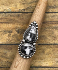 Silver ring with black stones on a wooden stick