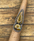 Intricate artisan made sterling ring with mountain turquoise stones and silver detailing on a wooden stick