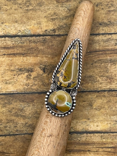 Intricate artisan made sterling ring with mountain turquoise stones and silver detailing on a wooden stick