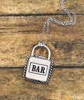 Silver padlock-shaped pendant with 'BAR' on a chain against a wooden background