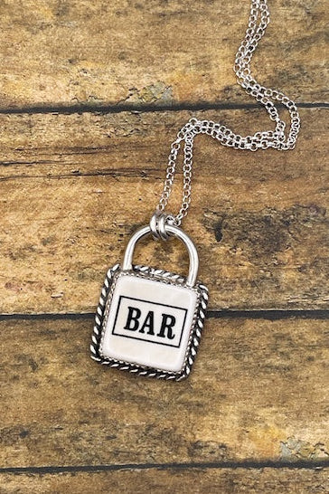 Silver padlock-shaped pendant with 'BAR' on a chain against a wooden background
