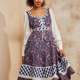 Woman wearing a floral dress with a patterned headscarf against a beige background