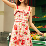 Woman in a floral summer sundress standing in front of a fruit stand.