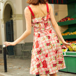 Back view of a woman in a pink floral dress with red adjustable straps.