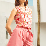 Woman wearing a pink outfit with sunglasses in a sunlit outdoor setting