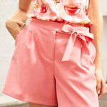 Woman wearing a pink outfit with a floral top and shorts.