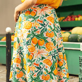 Person wearing a bright yellow top and a colorful skirt with fruit pattern in an outdoor setting.