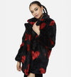 Woman in black fur jacket with red heart pattern
