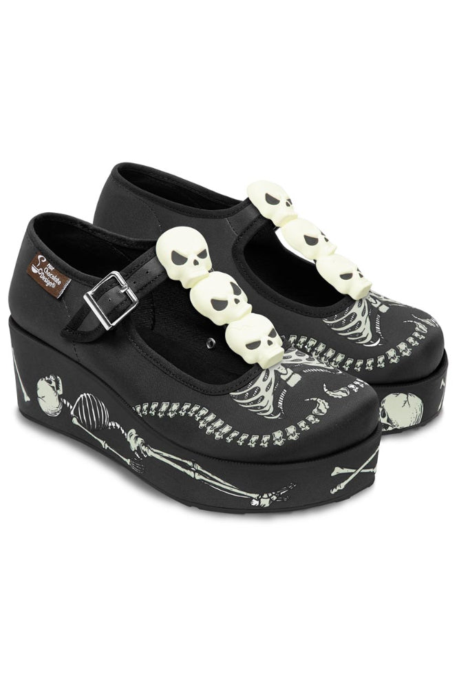Black platform shoes with skeleton design and skull embellishments on a white background