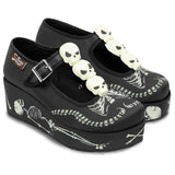 Black platform shoes with skeleton design and skull embellishments on a white background