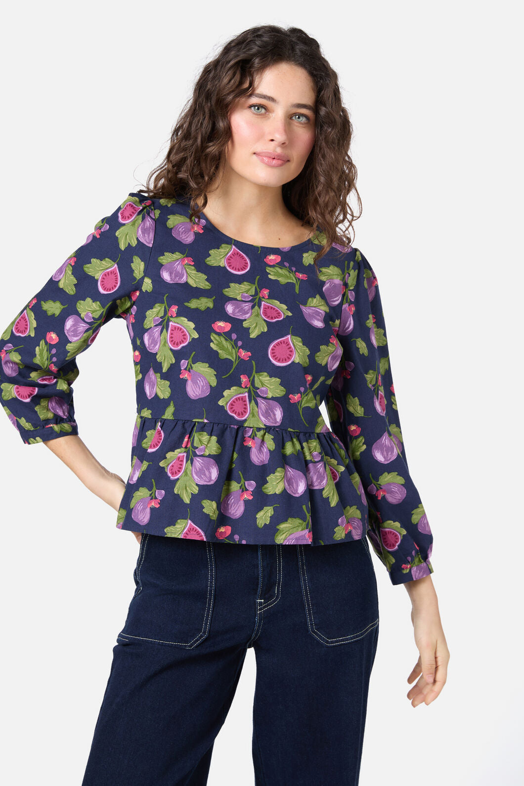 Woman wearing a navy blue top with fruit pattern on a white background
