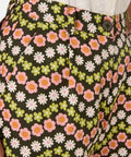 Floral patterned pants with a button detail on a dark background
