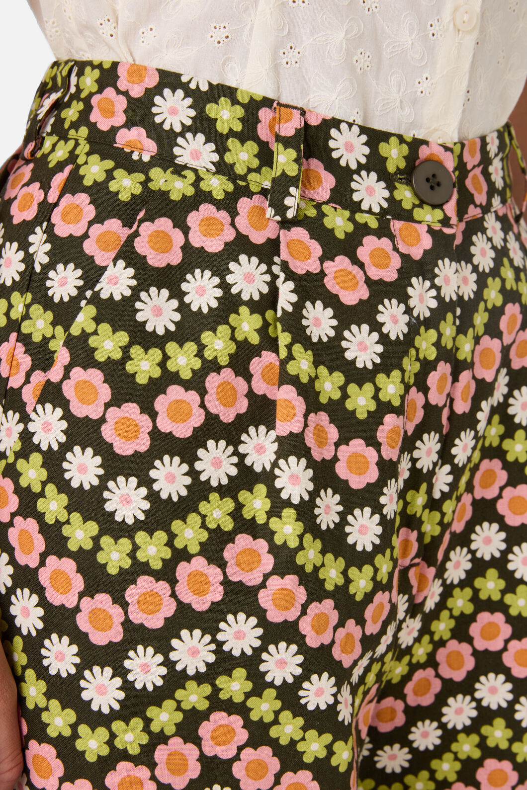 Floral patterned pants with a button detail on a dark background