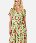 Woman wearing a green dress with red apple pattern on a white background