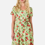 Woman wearing a green dress with red apple pattern on a white background