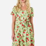 Woman wearing a green dress with red apple pattern on a white background