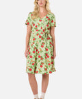 Woman wearing a green dress with red apple pattern on a white background