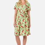 Woman wearing a green dress with red apple pattern on a white background