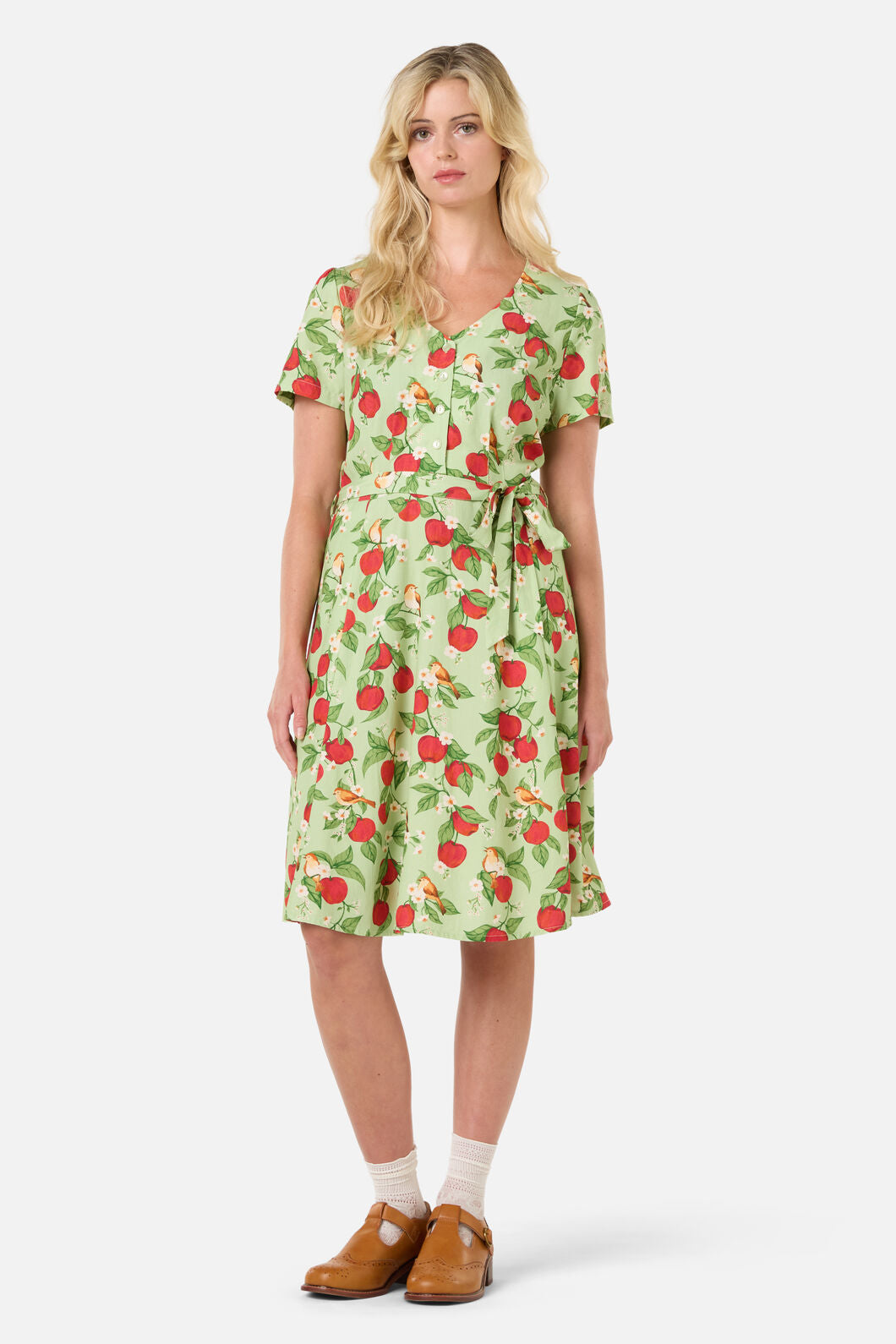 Woman wearing a green dress with red apple pattern on a white background