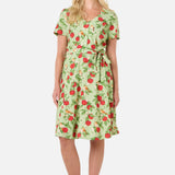 Woman wearing a green dress with red apple pattern on a white background